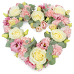 A softly coloured, heart-shaped floral wreath fills the frame, carefully arranged against a bright white background that highlights every bloom and curve. The heart is richly packed with creamy yellow and ivory roses, each rose fully formed, with velvety petals spiralling outward in calm, symmetrical layers. Nestled among them are generous clusters of pastel pink carnations whose finely frilled petals introduce a cloud-like softness and comforting texture. Deeper rose and mauve-pink lisianthus flowers, some with darker centres, are scattered thoughtfully through the design, adding pockets of richer tone and a sense of gentle depth, like memories held close. Woven between the flowers are stems of silvery-green eucalyptus, their round leaves offering a cool, tranquil contrast in both colour and texture, and lending the wreath subtle structure without disturbing its tenderness. Small yellowish-green buds peek from between petals, suggesting freshness and the quiet continuation of life. The overall composition is dense and luxurious, the heart outline smooth and unbroken, as if the flowers are holding one another in place. In the context of Vauxhall, this style of tribute might be chosen by a family saying goodbye at a local crematorium or gathering after a service near Kennington or Oval, the flowers travelling carefully from Flower Delivery Vauxhall. The wreath's pastel palette and heart shape together express enduring love, remembrance, and sympathy, offering a gentle visual comfort to those in mourning. It is a design that feels appropriate for funerals, memorial services, or anniversaries of loss, where a soft, dignified expression of emotion is needed.